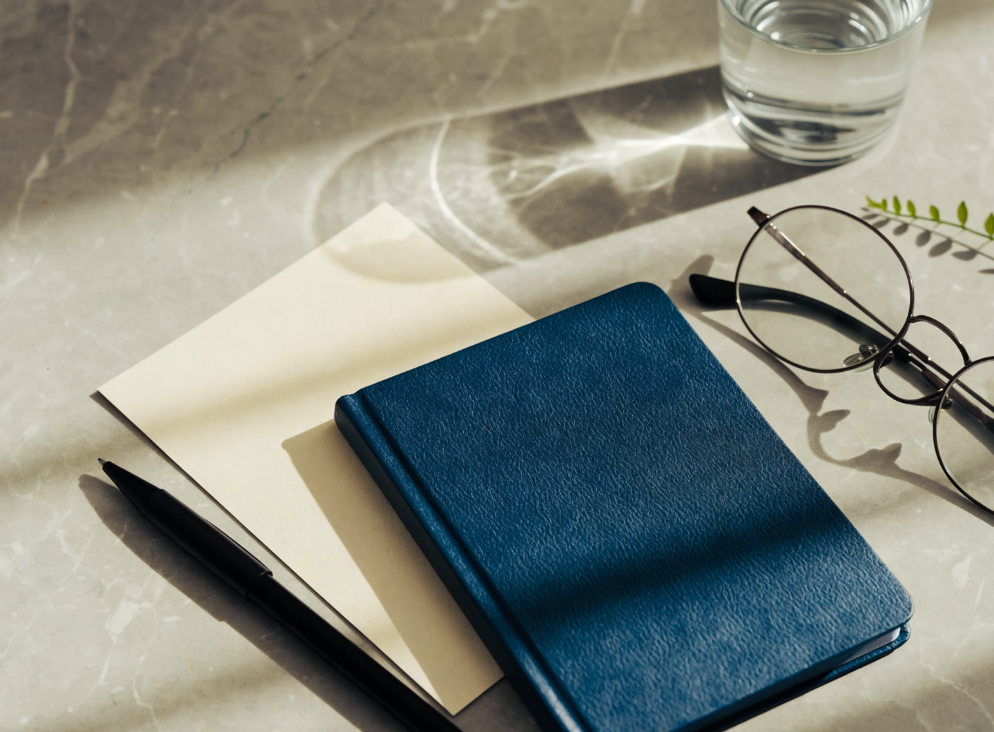 A notebook, pen and reading glasses arranged in natural light